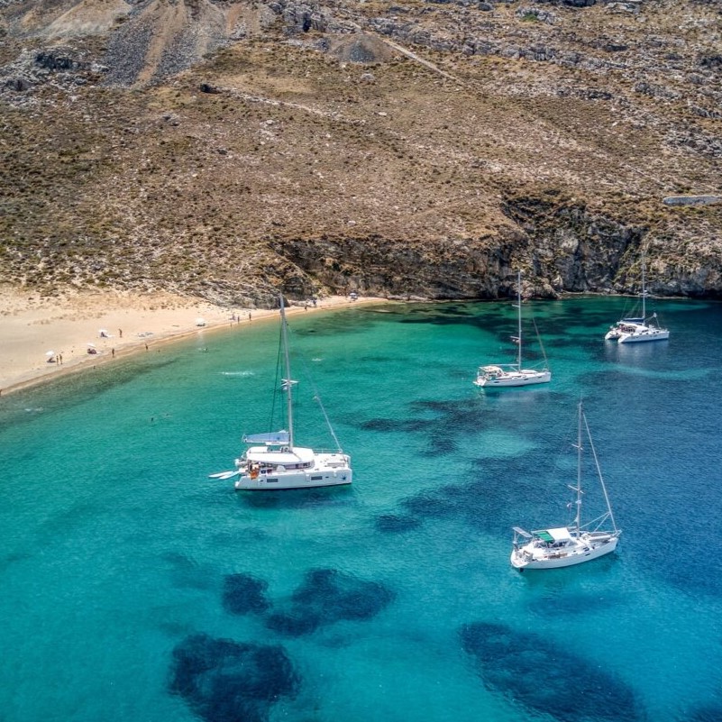 Sailing catamarans anchored in a turquoise bay on Serifos island in the Greek Cyclades.