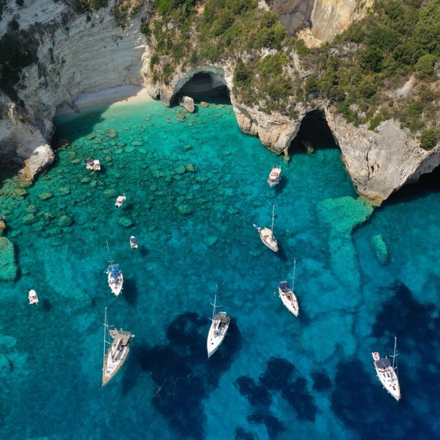 Aerial drone photo of paradise bay an caves of blue lagoon in beautiful island of Paxos visited by yachts and sail boats, Ionian, Greece